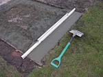 Using screed with shovel to make a  small concrete slab.