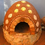 Cooking in finished earth clay cob bread and pizza oven.