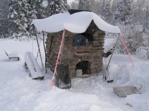 Winter snow around and on top of oven.