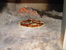 How to place pizza onto ovens floor with ongoing fire.