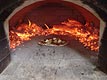 Picture of wood fired pizza in barrel-dome oven.