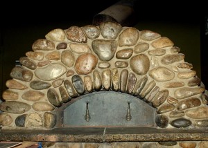 Igloo pizza oven covered in river rock or stone pebbles.