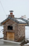 Cooking in wood fired pizza oven during snowy winter