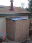 Inside oven is outside behind house wall and chimney.